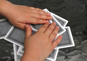 closeup of two kid hands over a pile of playing cards