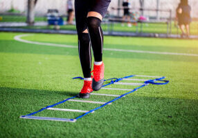 Young boy soccer players Jogging and jump between ladder drills for football training. Ladder drills exercises for football or soccer team. Kid soccer player exercises on ladder drills.